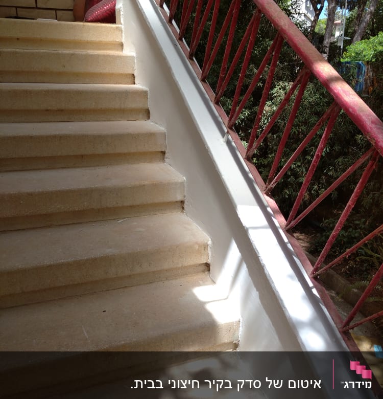 מדרגות אבן עם מעקה מתכת אדום